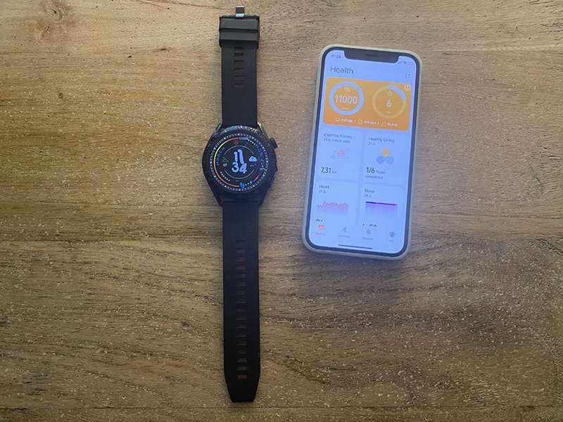 Часы Huawei Watch GT 3 на столе рядом с мобильным телефоном.